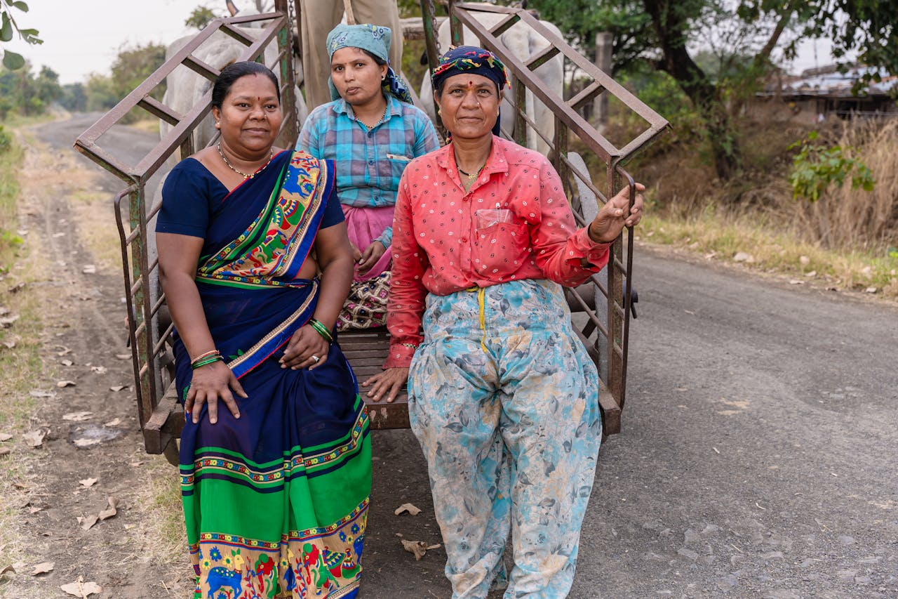 Three women farmers in traditional attire pose on a rural path in Nagpur, India.